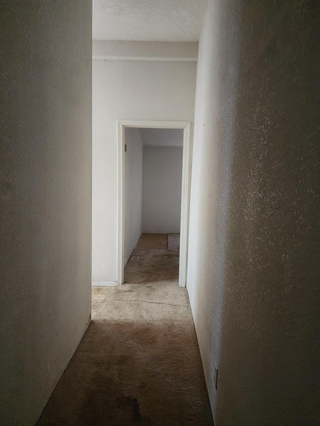 hallway with a textured ceiling and light colored carpet