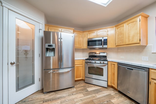 kitchen featuring decorative backsplash, light hardwood / wood-style floors, light brown cabinets, and appliances with stainless steel finishes