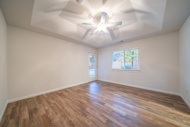 unfurnished room featuring a raised ceiling and dark wood-type flooring