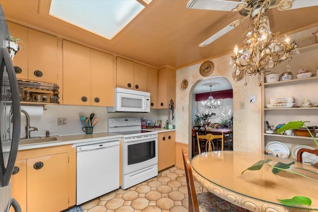 kitchen featuring ceiling fan with notable chandelier, pendant lighting, white appliances, and sink