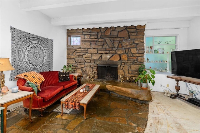 living room with a stone fireplace and beamed ceiling