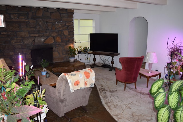 living room with beamed ceiling and a stone fireplace