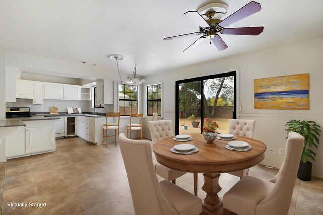 dining space featuring sink and ceiling fan with notable chandelier