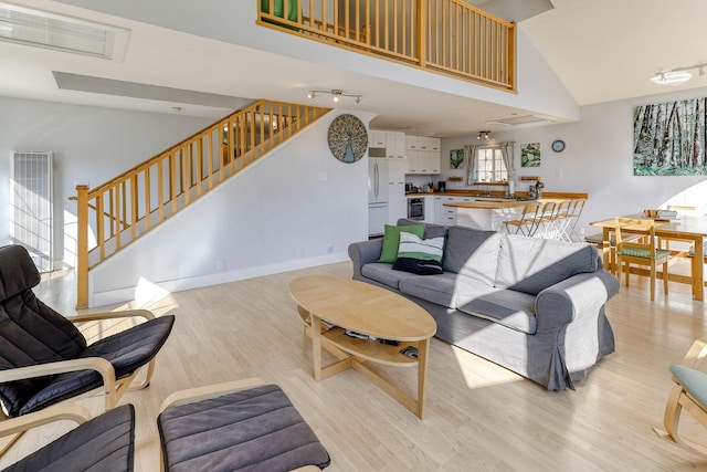 living room featuring light hardwood / wood-style flooring and high vaulted ceiling