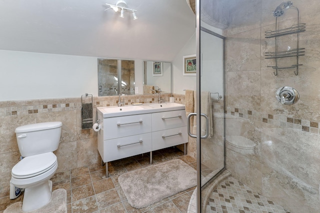 bathroom with a shower with door, tile walls, vaulted ceiling, toilet, and vanity