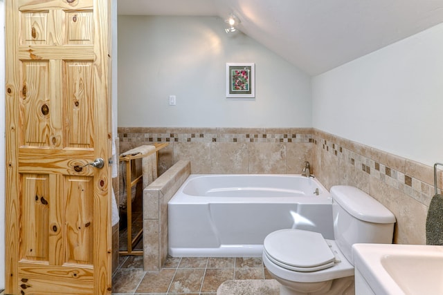 bathroom with lofted ceiling, toilet, tile patterned flooring, a bathing tub, and tile walls