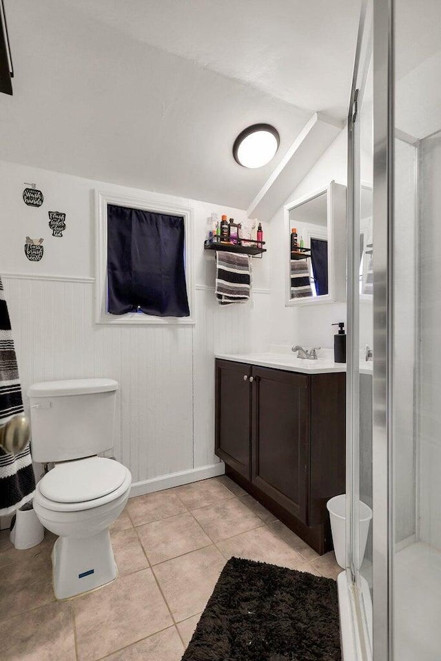 bathroom featuring lofted ceiling, a shower with door, toilet, vanity, and tile patterned flooring