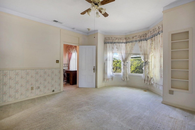 unfurnished room featuring ornamental molding, carpet flooring, built in features, and ceiling fan