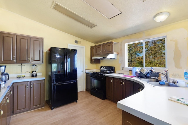 kitchen featuring lofted ceiling, dark brown cabinets, light wood-type flooring, black appliances, and sink