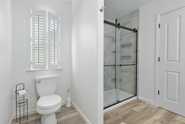 bathroom with wood-type flooring, toilet, and a shower with shower door