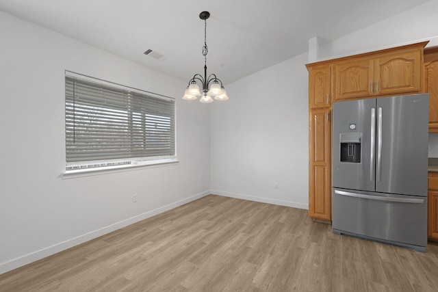 kitchen featuring pendant lighting, lofted ceiling, a notable chandelier, stainless steel refrigerator with ice dispenser, and light wood-type flooring