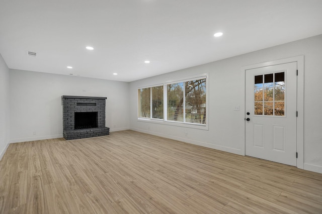 unfurnished living room with light hardwood / wood-style flooring and a brick fireplace