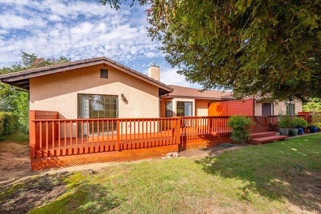 rear view of property with a deck and a lawn