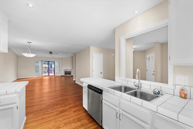 kitchen with tile countertops, white cabinets, stainless steel dishwasher, and sink