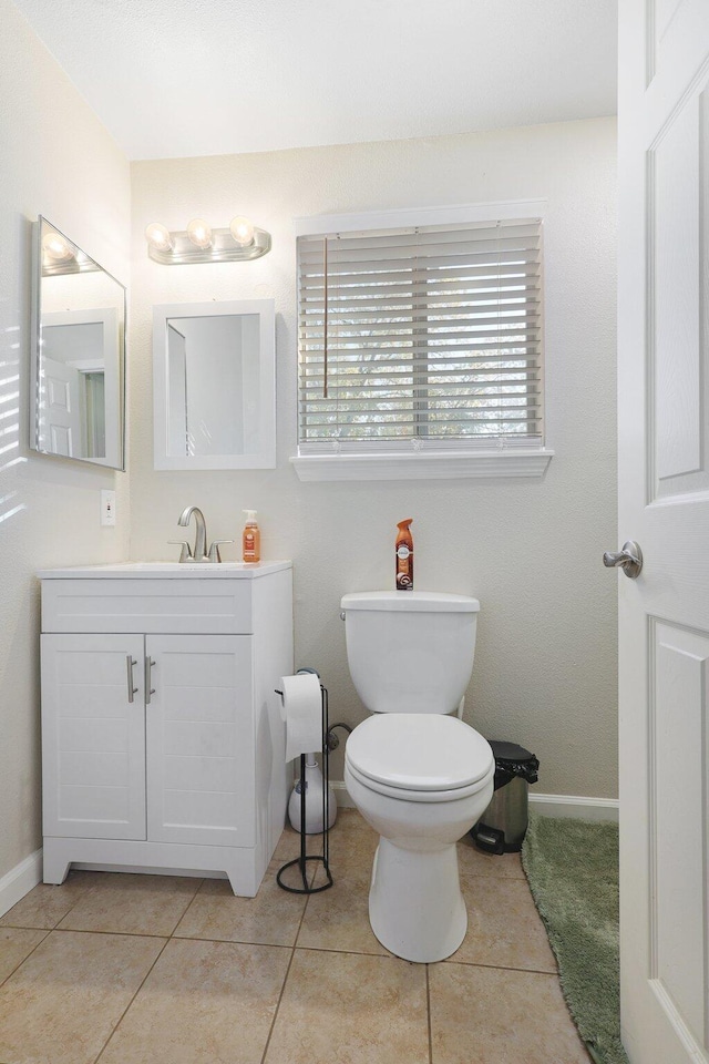 bathroom with a wealth of natural light, vanity, toilet, and tile patterned flooring