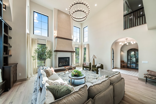 living room with a towering ceiling, a fireplace, light wood-type flooring, and plenty of natural light