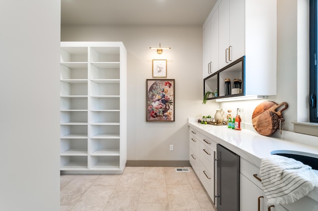 kitchen featuring light countertops, white cabinets, refrigerator, open shelves, and baseboards