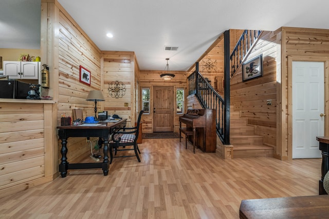 foyer entrance with wooden walls and light hardwood / wood-style floors