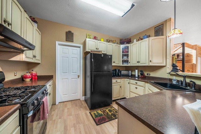 kitchen featuring light wood-type flooring, sink, black appliances, cream cabinets, and decorative light fixtures