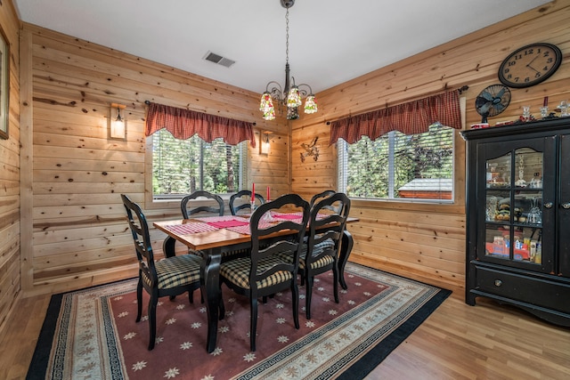 dining area featuring wood-type flooring, a wealth of natural light, and wooden walls