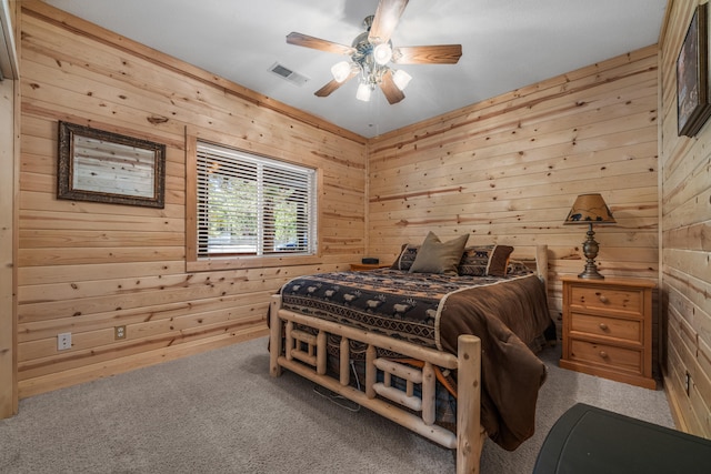 bedroom featuring ceiling fan, wooden walls, and carpet