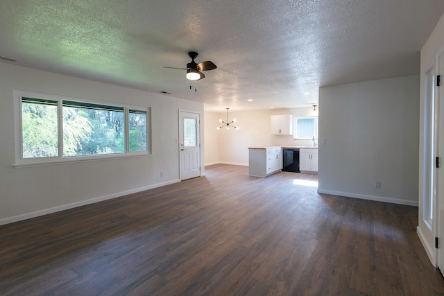 unfurnished living room featuring dark wood-type flooring, a textured ceiling, and ceiling fan with notable chandelier