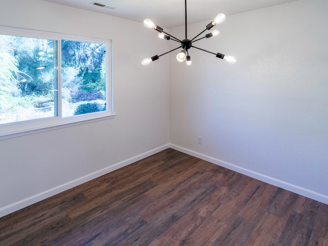 empty room featuring an inviting chandelier and dark hardwood / wood-style flooring