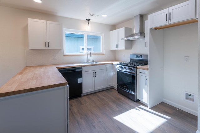 kitchen with wall chimney range hood, white cabinets, black dishwasher, wood counters, and stainless steel range with gas stovetop