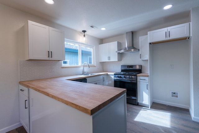 kitchen featuring sink, wood counters, white cabinetry, wall chimney exhaust hood, and gas range