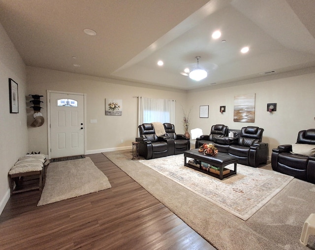 living room with hardwood / wood-style floors and a raised ceiling