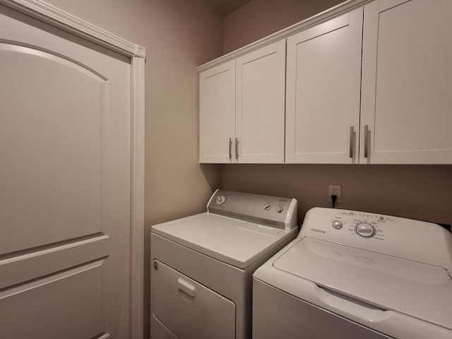 clothes washing area featuring cabinets and independent washer and dryer