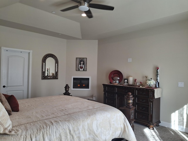 carpeted bedroom with a tray ceiling and ceiling fan