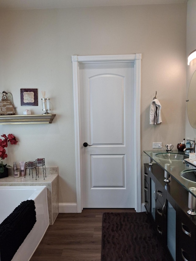 bathroom with a bath, hardwood / wood-style floors, and vanity