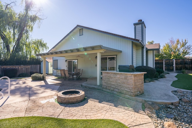 rear view of property with a fire pit, a patio, a chimney, and fence