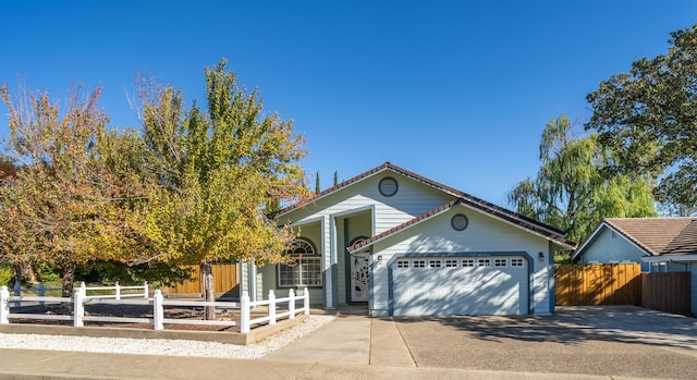 view of front of house with concrete driveway, a fenced front yard, and an attached garage