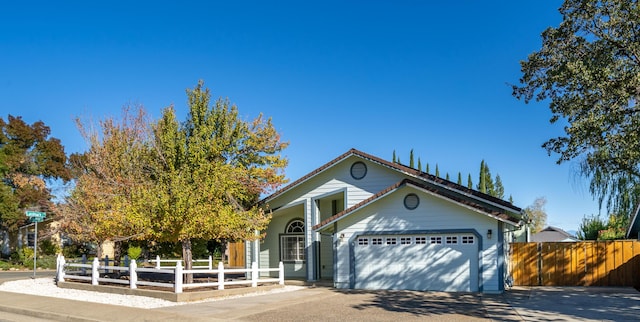 view of front of property featuring fence, driveway, and an attached garage