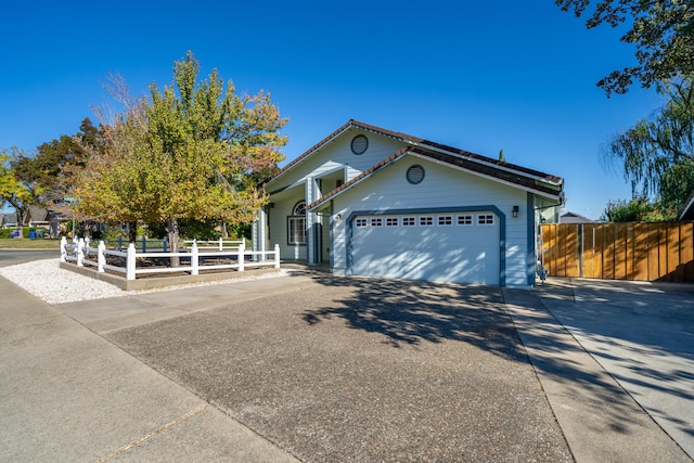 view of front of house with driveway, a garage, and fence