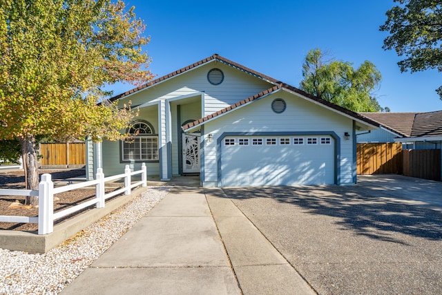 view of front of property featuring a garage, concrete driveway, a fenced front yard, and a tiled roof