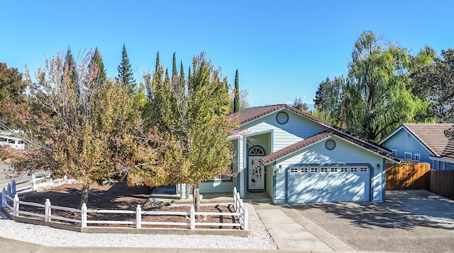 view of front facade featuring driveway, an attached garage, and fence