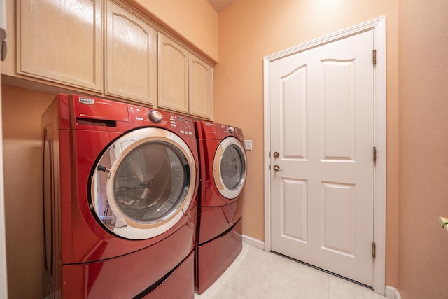 laundry area with light tile patterned floors, washing machine and clothes dryer, cabinet space, and baseboards