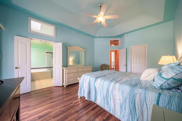 bedroom with connected bathroom, a ceiling fan, a raised ceiling, and dark wood-style flooring