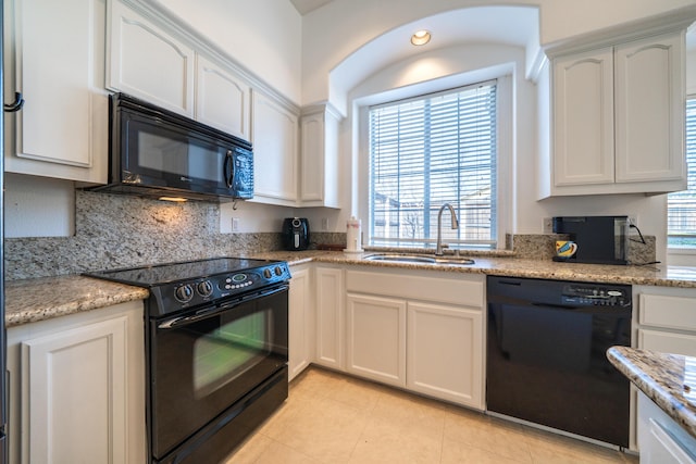 kitchen featuring white cabinetry, a sink, black appliances, and light stone countertops