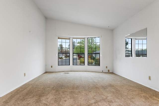 carpeted empty room featuring lofted ceiling and plenty of natural light