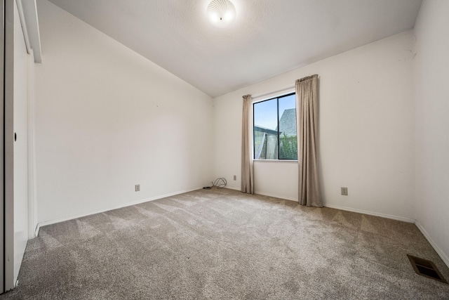 carpeted spare room featuring vaulted ceiling