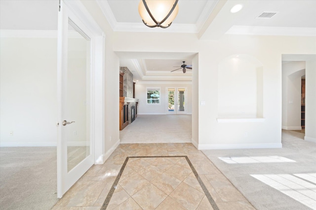 hall with a tray ceiling, french doors, light carpet, and ornamental molding