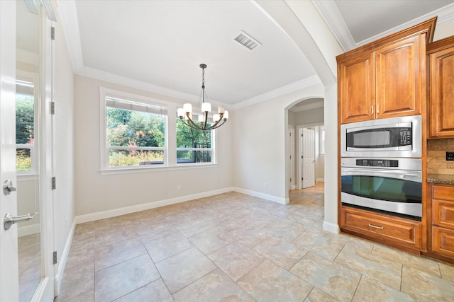 kitchen featuring dark stone counters, a notable chandelier, tasteful backsplash, ornamental molding, and appliances with stainless steel finishes