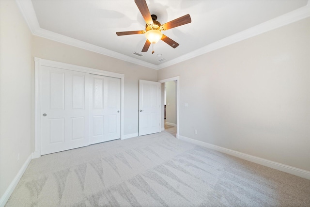 unfurnished bedroom featuring ceiling fan, light carpet, a closet, and crown molding