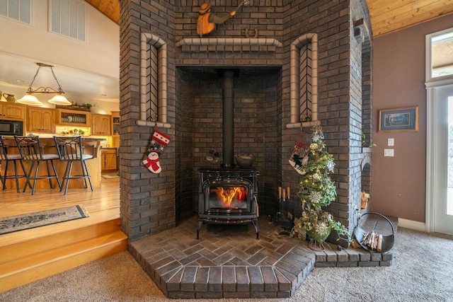 carpeted living room with a wood stove and high vaulted ceiling