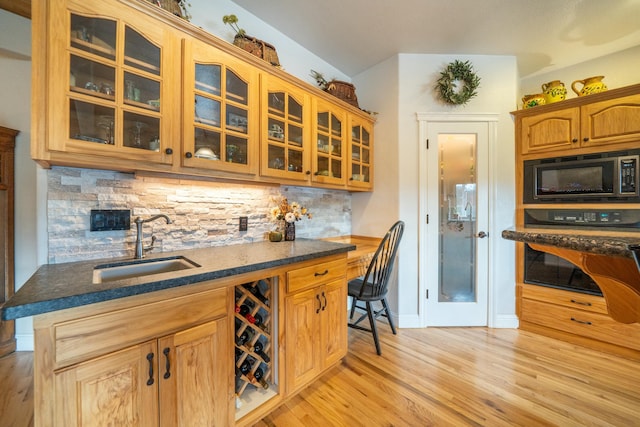 kitchen featuring stainless steel microwave, backsplash, sink, black oven, and light hardwood / wood-style floors