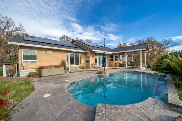 view of swimming pool with pool water feature, a patio area, and a hot tub